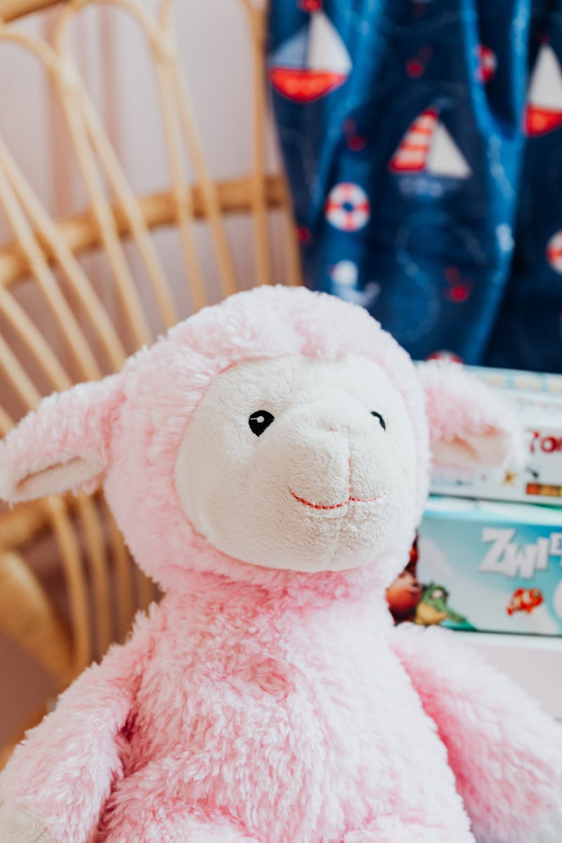 Charming pink stuffed sheep toy sits on a chair, adding a cute touch to a cozy room decor.